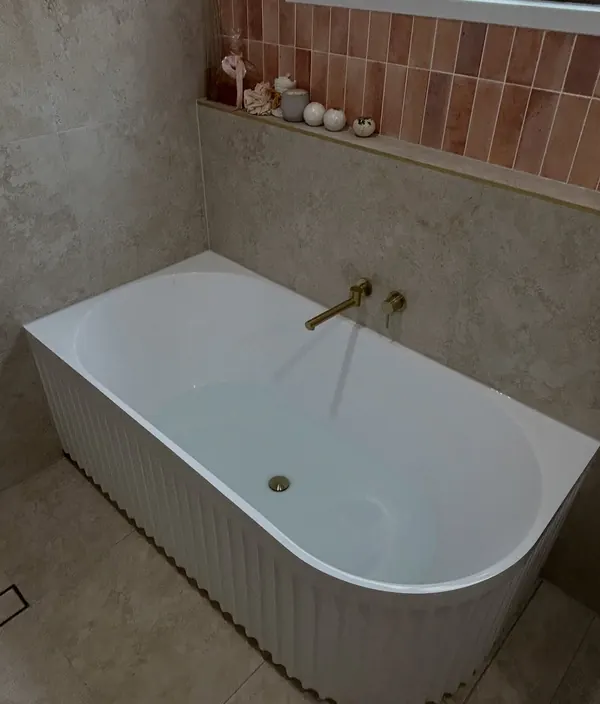 Bath installed with a brass wall spout and mixer against tiling