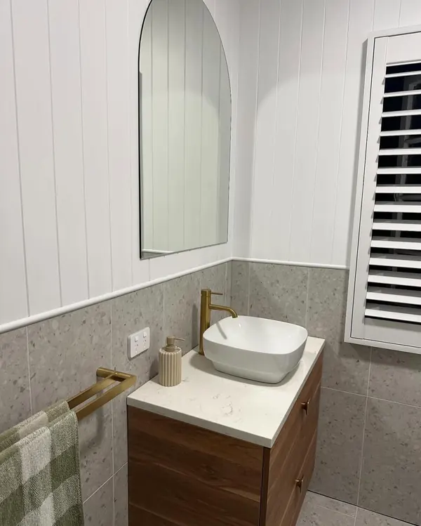 Completed bathroom with a stone-top vanity, vessel basin and brass tapware