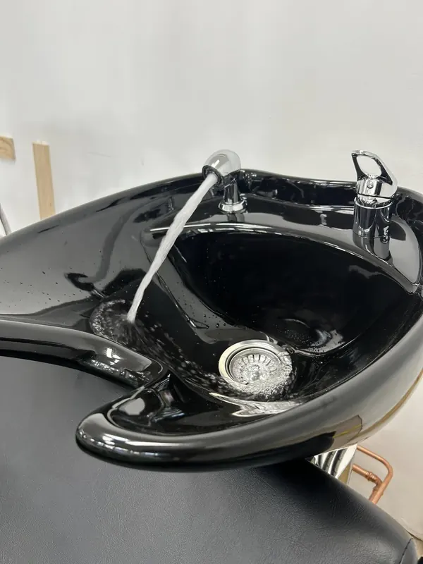 Black basin with a new mixer tap and waste, freshly installed