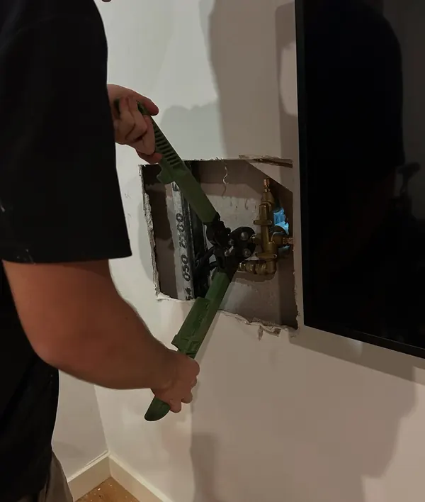 Cutting into a wall to reach concealed pipework for a repair