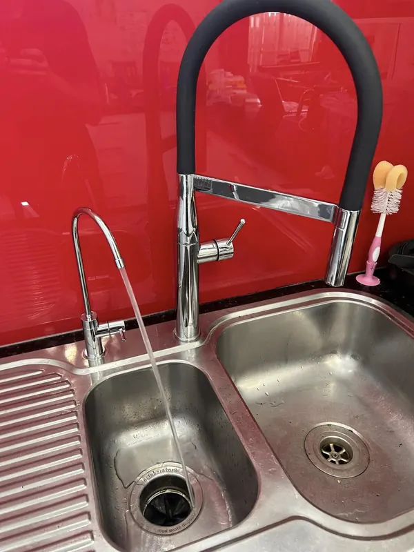 Stainless double-bowl sink and mixer tap installed against a red splashback