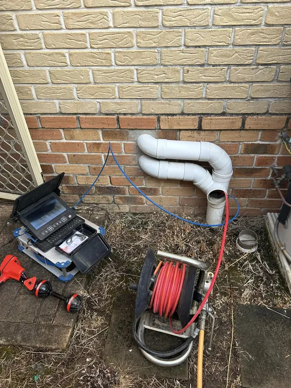 Downpipe and drain camera equipment set up against a brick wall