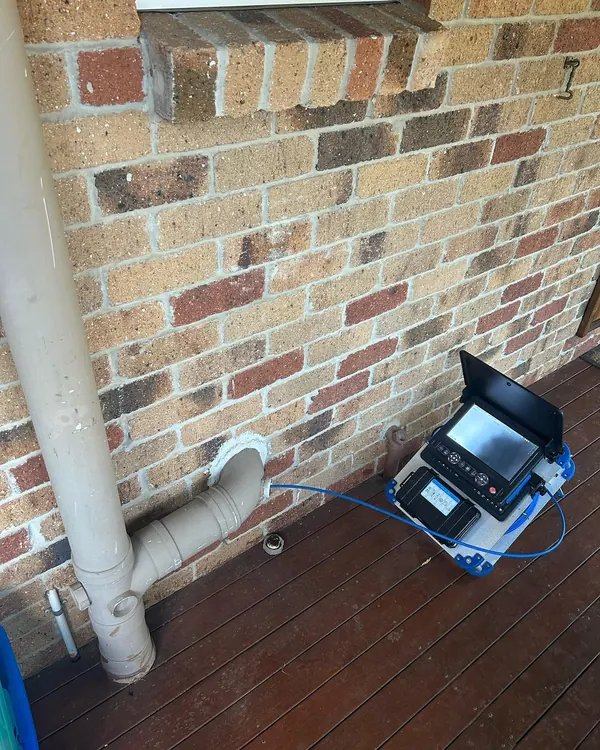 CCTV drain camera and monitor set up beside a downpipe to inspect an underground line