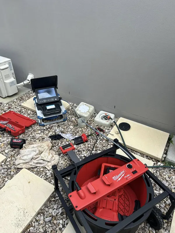 Drain camera monitor and hand tools laid out on site during an inspection