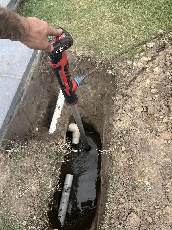 Open trench with a new PVC section joined into an existing underground drain
