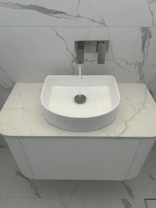 Fluted vanity with a stone top, basin and wall-mounted mixer