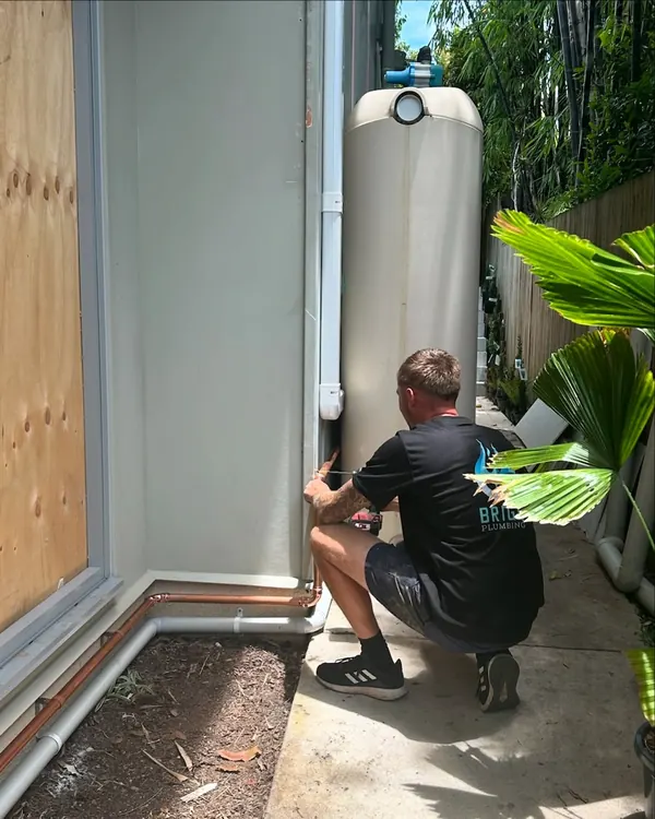 Plumber connecting the pipework to a newly installed heat pump hot water unit