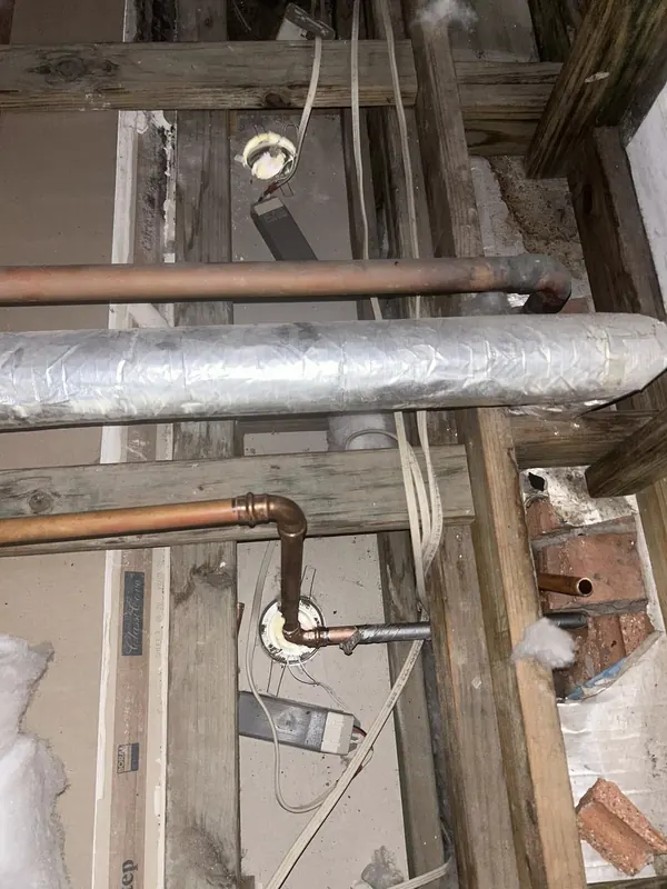 Insulated hot and cold copper pipework run through a subfloor