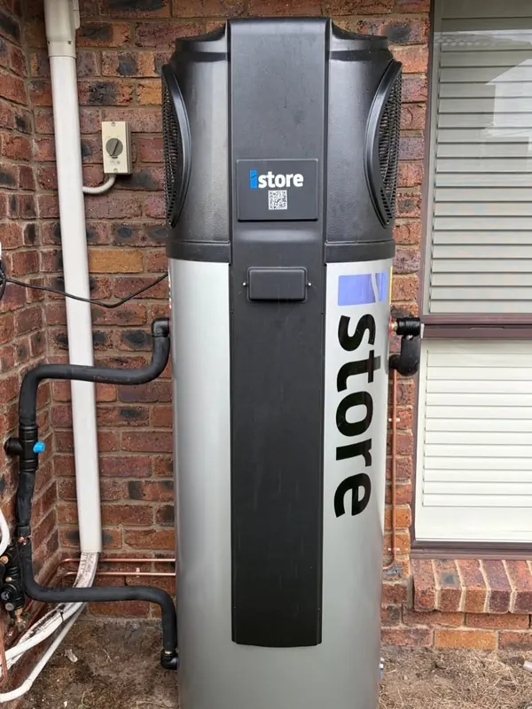 iStore heat pump hot water unit installed against a brick wall