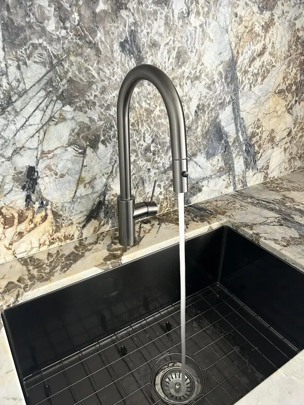 Kitchen sink and gooseneck mixer installed in a stone benchtop