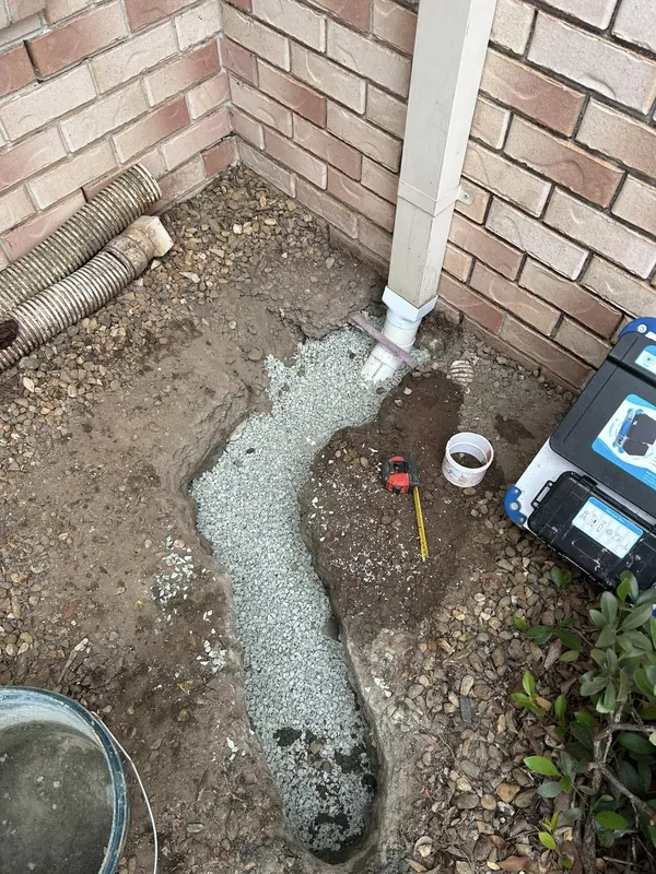 Water leak located and exposed in a garden bed beside a downpipe