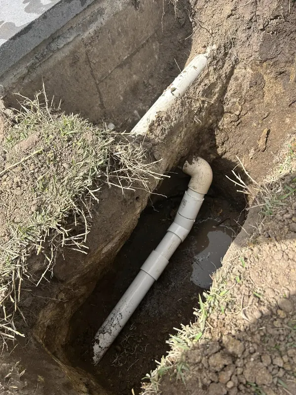 New drain line laid in an open trench before backfilling