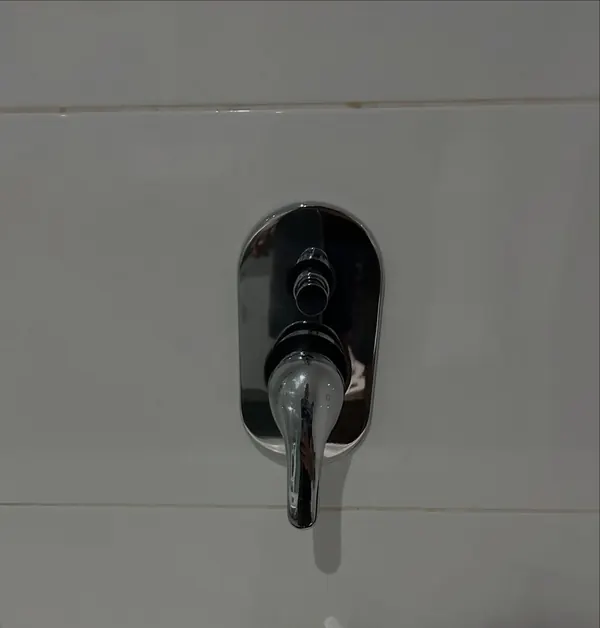 Black shower mixer installed in a tiled wall