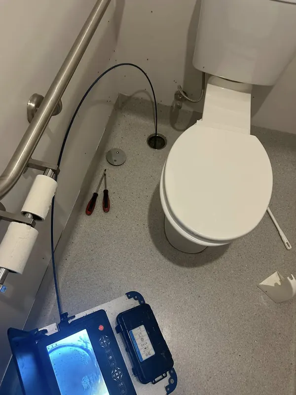 Toilet suite being connected, with tools and a drain camera alongside