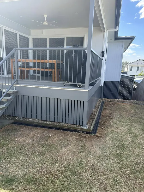 Completed yard and under-house drainage work beside a screened enclosure