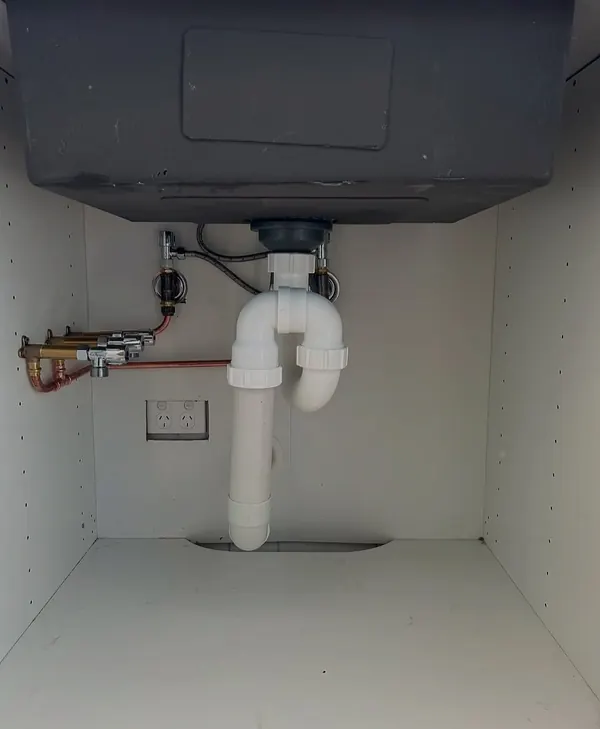 New waste and water pipework inside a kitchen cabinet
