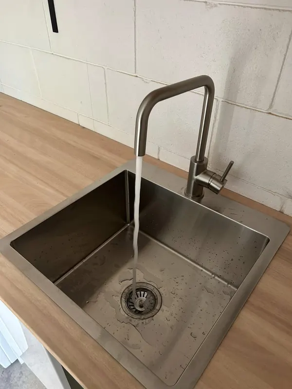 Stainless undermount sink with a gooseneck mixer running