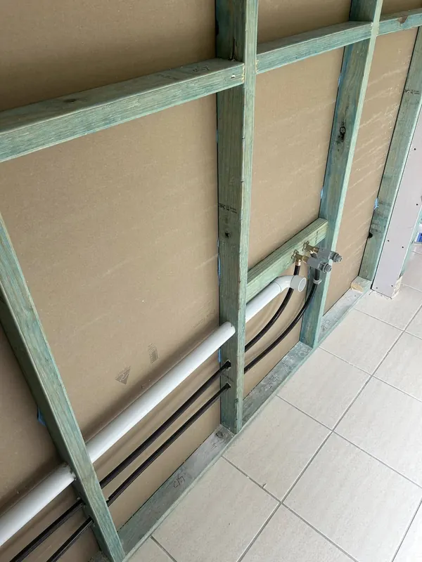 Water and waste rough-in pipework set into a stud wall before lining